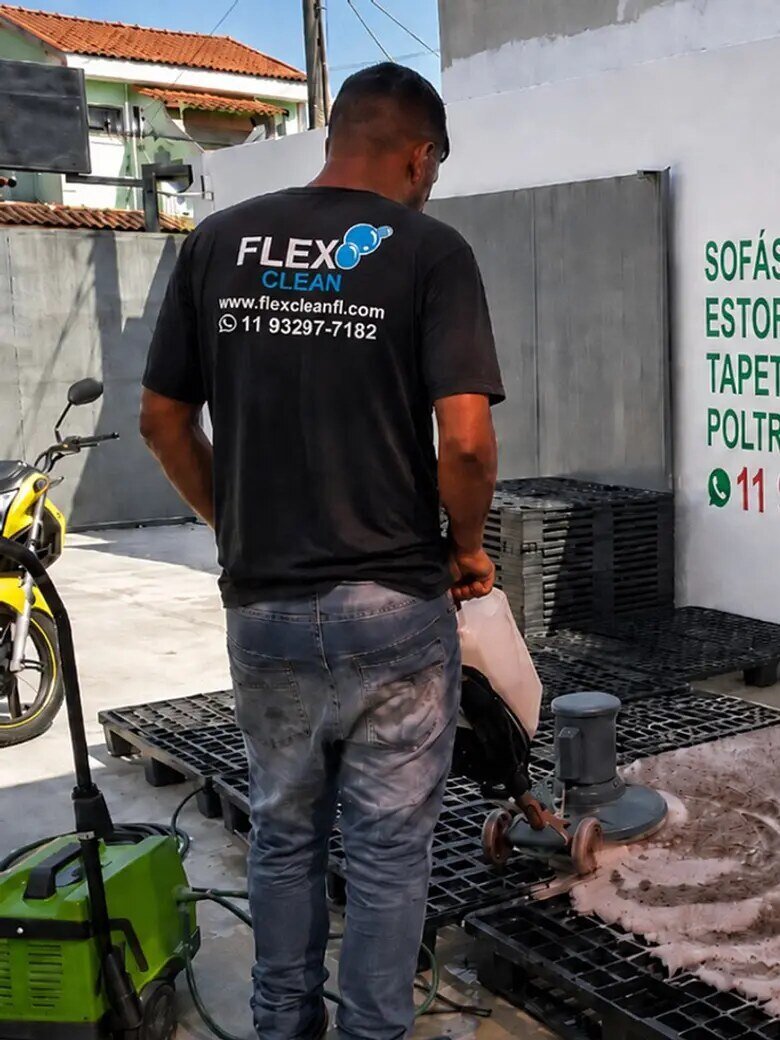 Técnico da Flex Clean lavando um tapete estendido no piso da lavanderia própria