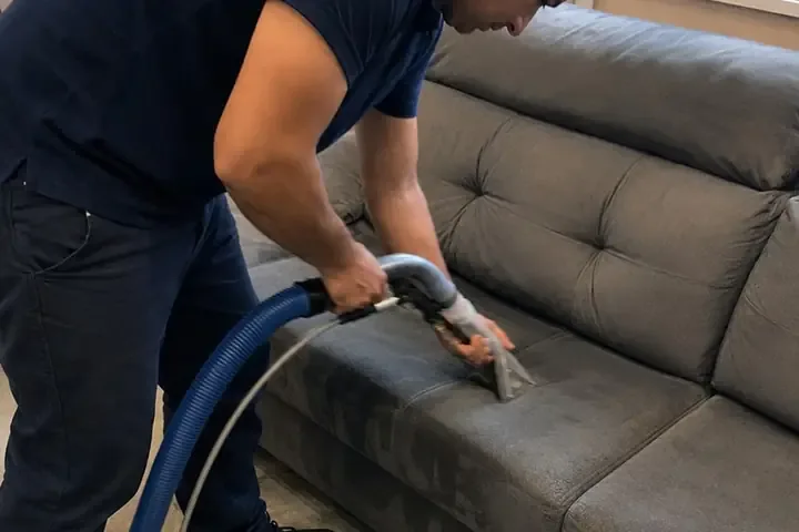 Técnico da Flex Clean aplicando o impermeabilizante no tecido de um sofá com equipamento pressurizado