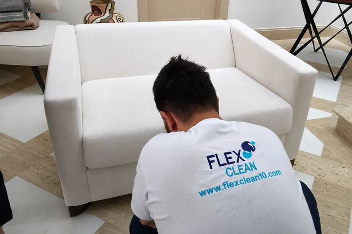 Profissional da Flex Clean tratando uma poltrona clara em ambiente residencial