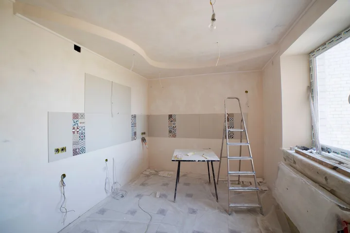 Cômodo recém-reformado, ainda com escada, mesa de apoio e resíduo no chão