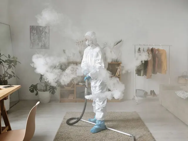 Profissional com equipamento de proteção nebulizando desinfetante em uma sala
